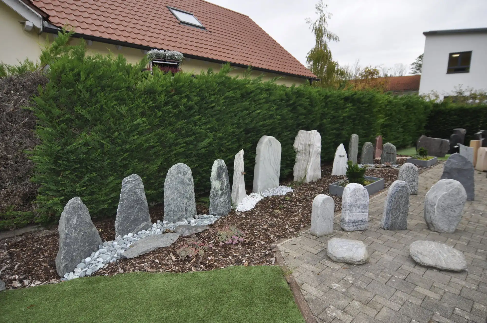 Findlinge und Natursteine vor einer Hecke im Freigelände